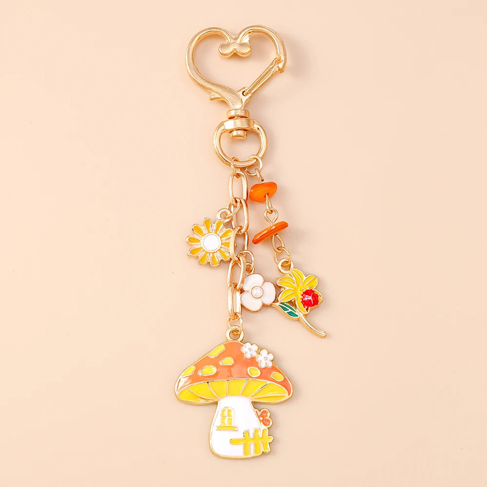 Breloque de sac en émail doré motif champignon avec maison-champignon orange, marguerite et fleurs, sur fond beige