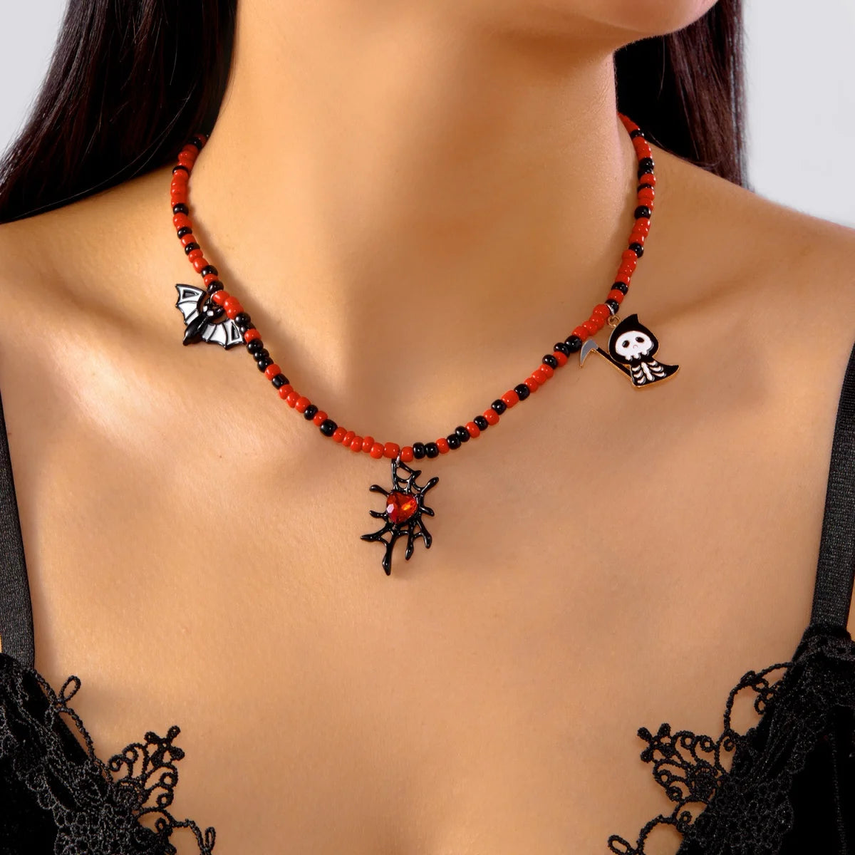 Collier Halloween en perles rouges et noires avec pendentifs chauve-souris, squelette et cœur toile d'araignée, porté autour du cou