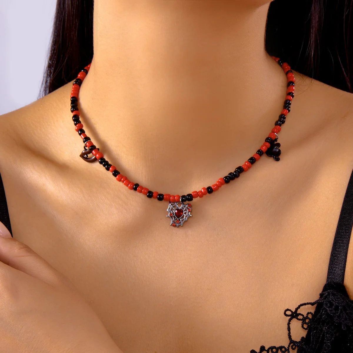 Collier Halloween en perles rouges et noires avec pendentif cœur toile d'araignée, porté autour du cou