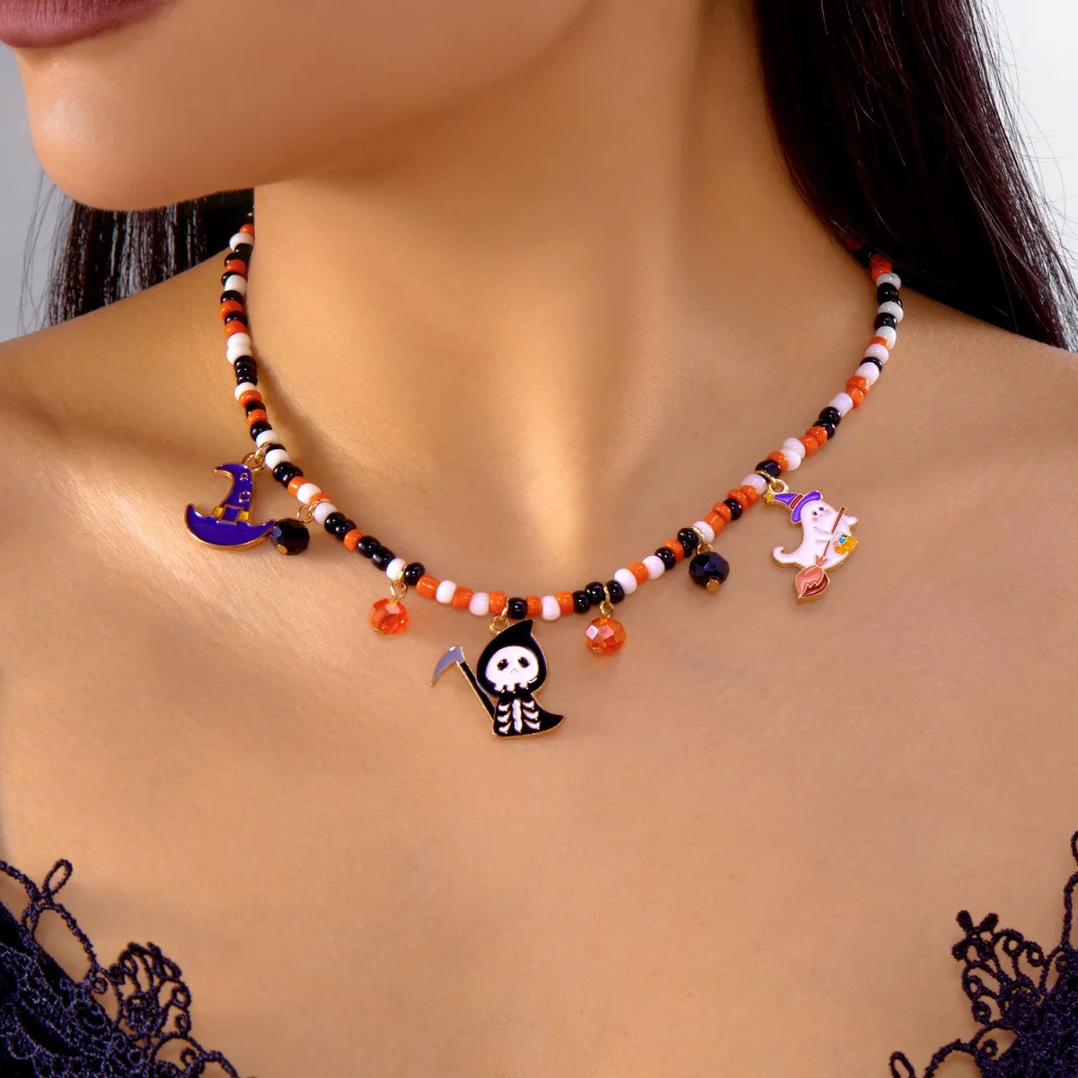 Collier Halloween en perles orange, blanches et noires avec pendentifs lune chapeau de sorcière, squelette et fantôme, porté autour du cou